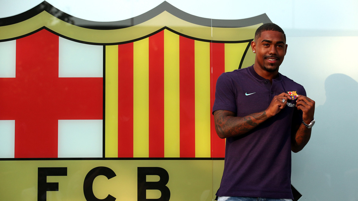 Brazilian soccer player Malcom Filipe Silva de Oliveira poses in front of a FC Barcelona logo at their offices next to Camp Nou stadium in Barcelona
