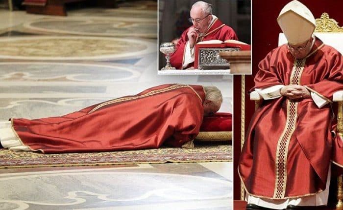 Pope Francis prostrates himself in St Peter's Basilica for Good Friday service as he rests his head on a red pillow and prays